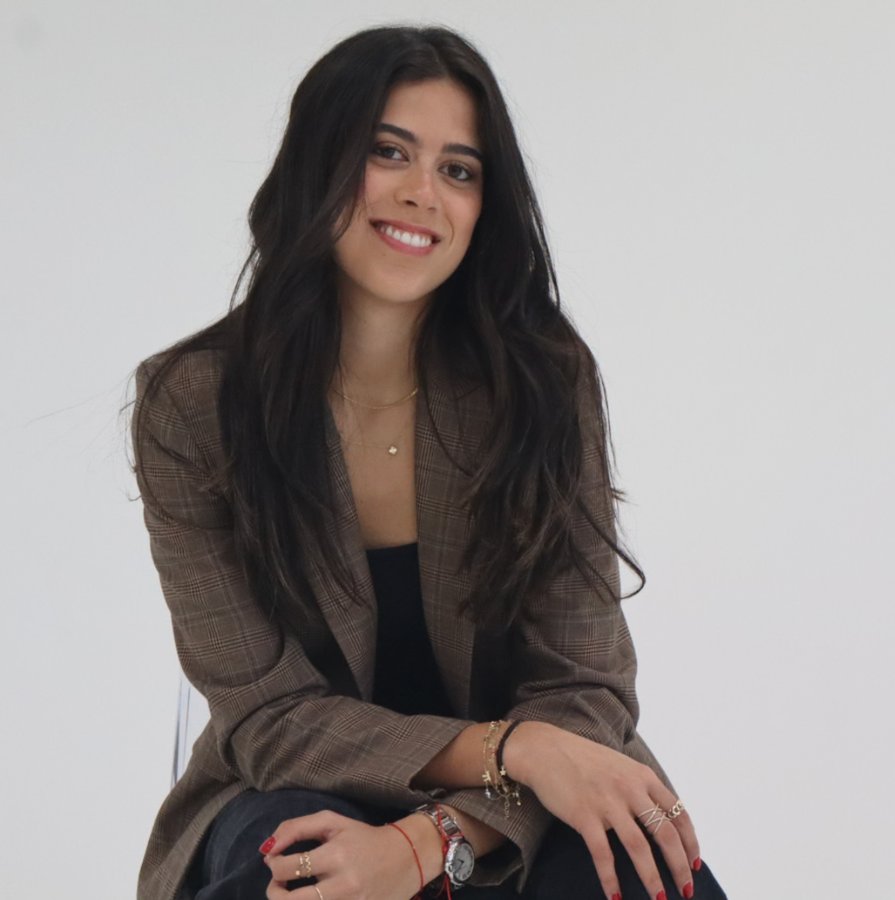 Cecile smiling, seated in a plaid blazer